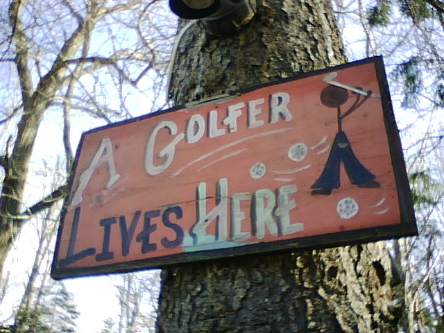 A sign with a golfer on it that says " A golfer lives here"