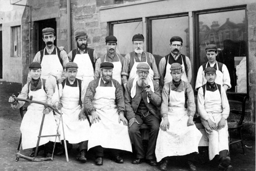 A vintage photo of Old Tom Morris and staff in from of his golf shop.