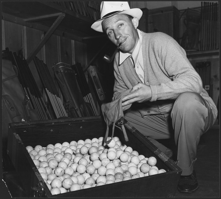 A photo of Bing Crosby with a large box of golf balls, getting ready to go to the range.