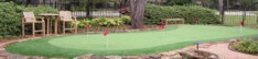 A photo of a back yard putting green with patio chairs.