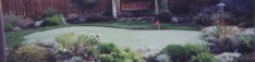 A photo of a back yard putting green with patio chairs.